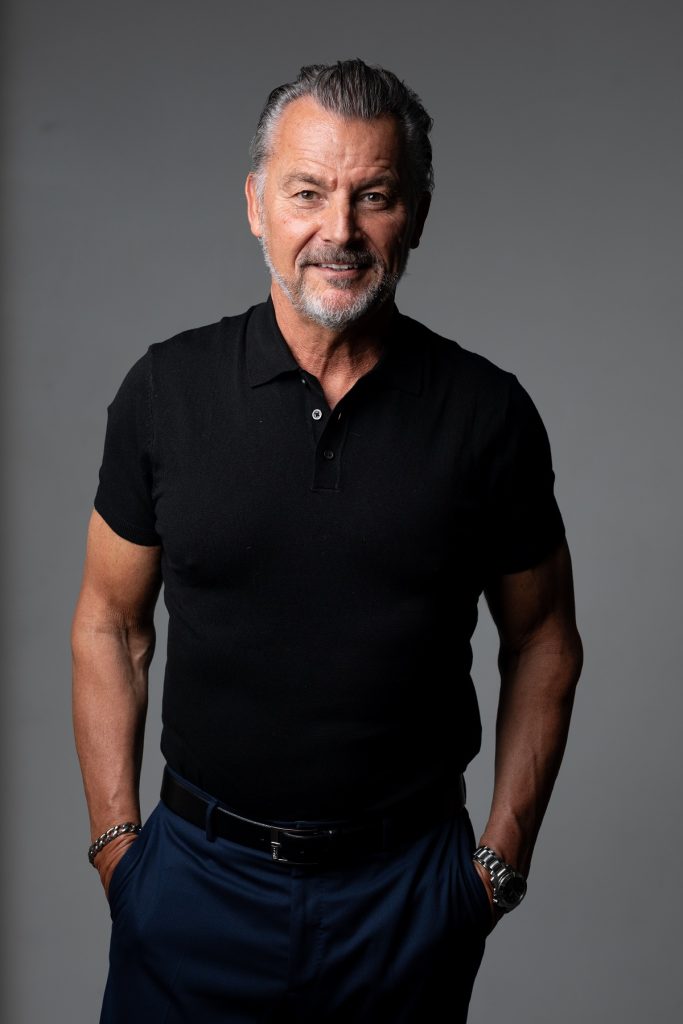 A man in black shirt and jeans posing for the camera.