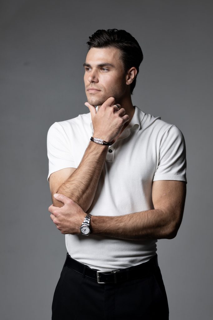 A man in white shirt holding his hand on neck.