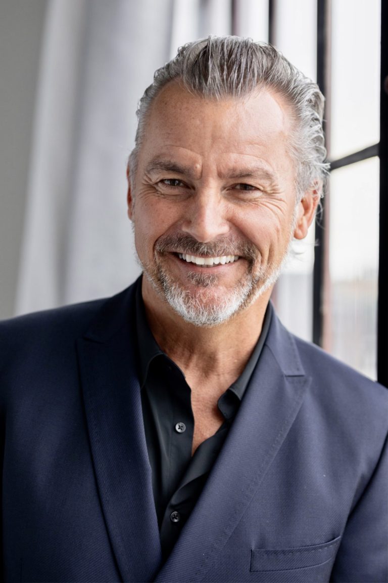 A man with grey hair and a black suit jacket.