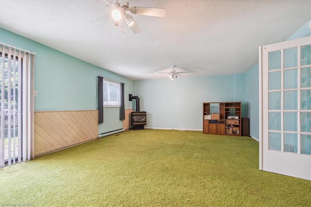 A room with green carpet and a fireplace.