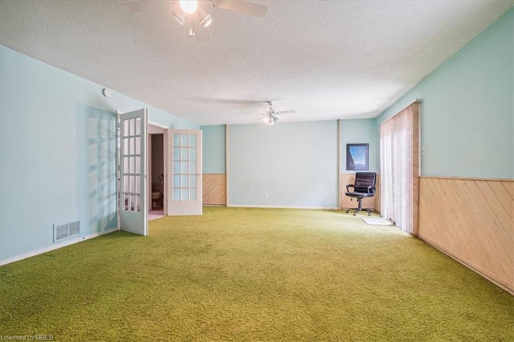 A room with green carpet and a chair.