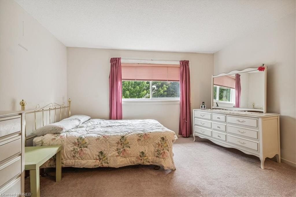 A bedroom with a bed, dresser and window.