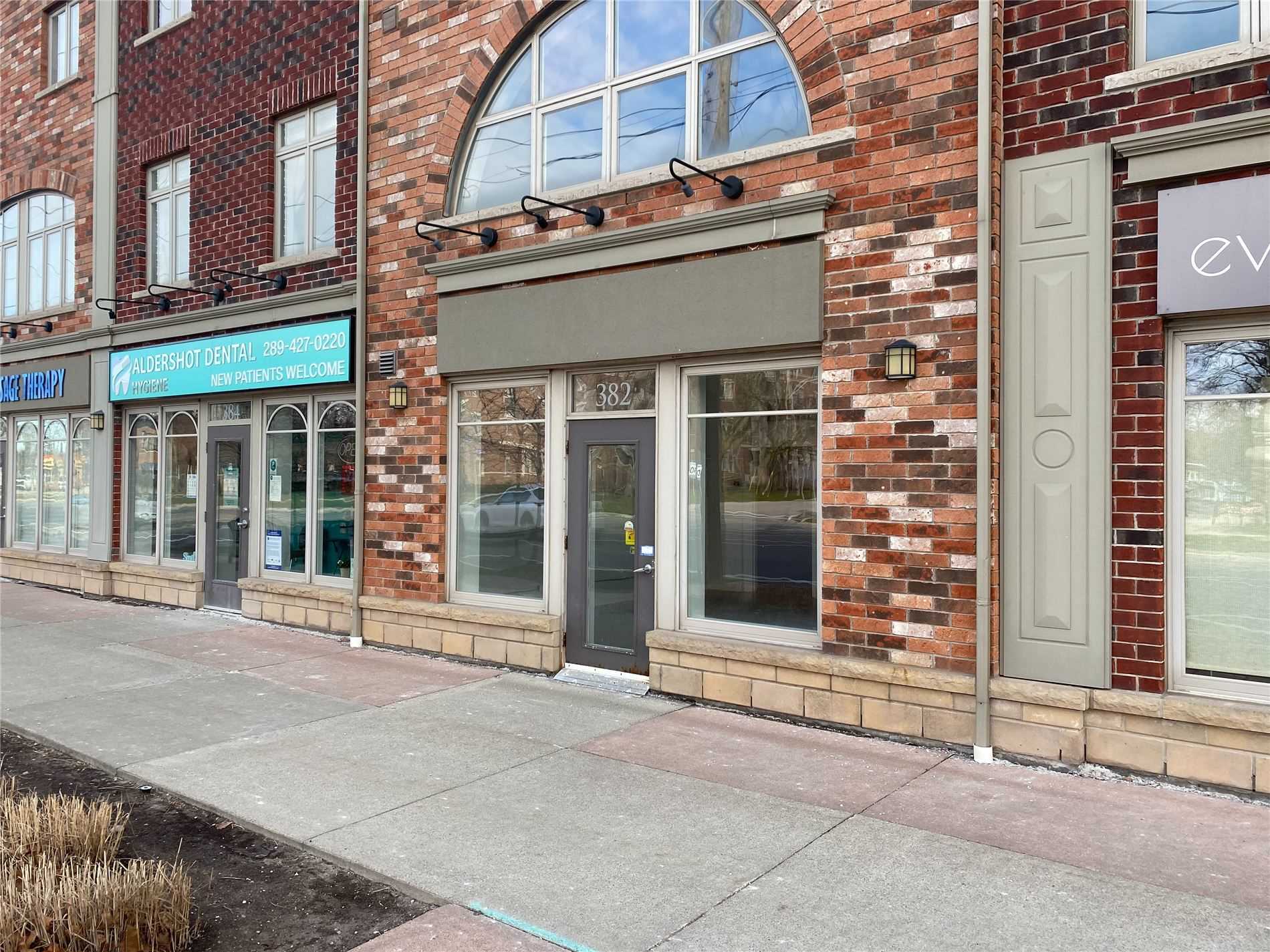 A brick building with two windows and a sidewalk.