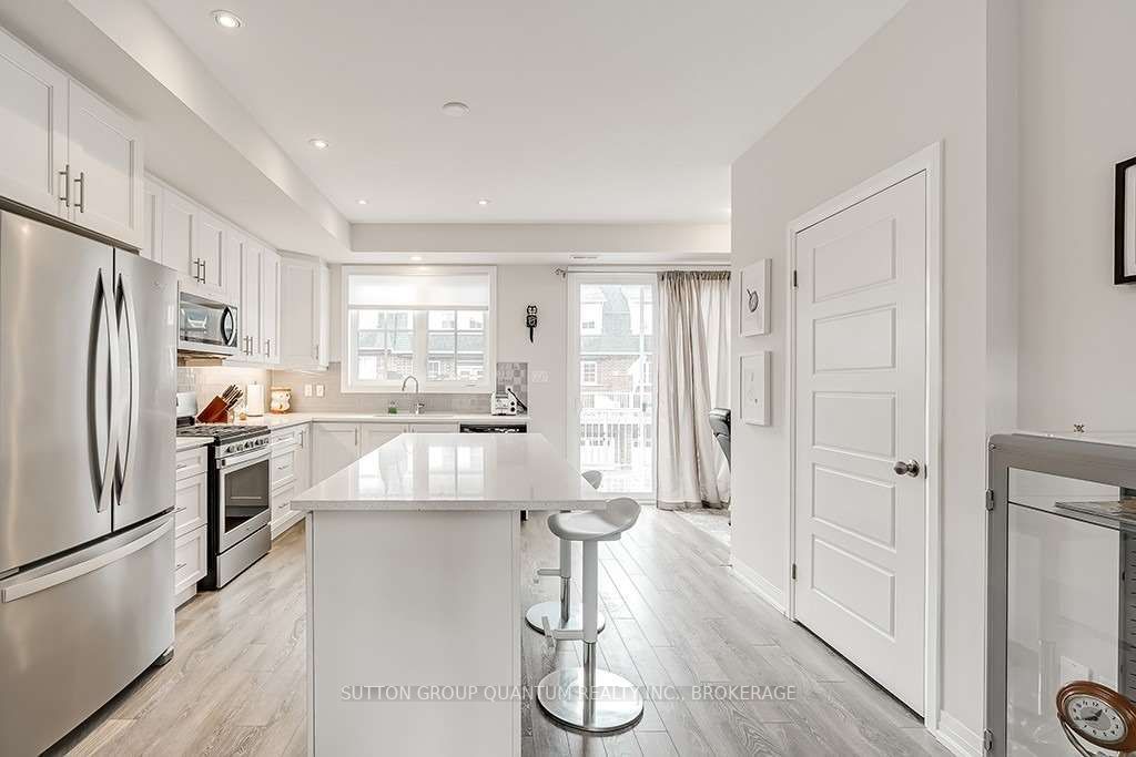 A kitchen with white cabinets and wood floors.