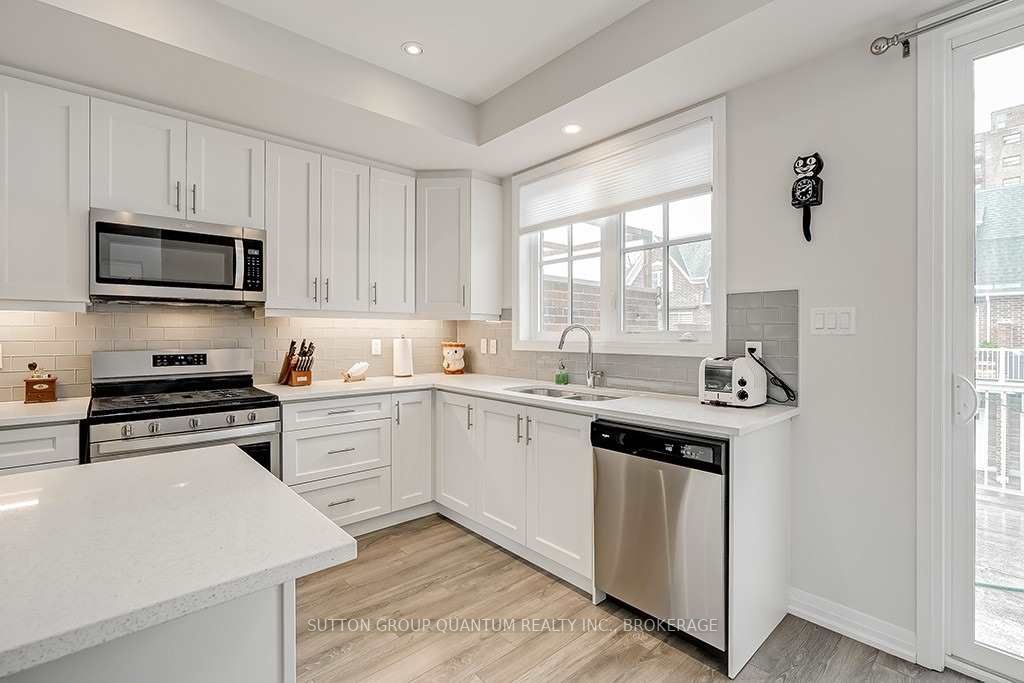 A kitchen with white cabinets and wood floors.