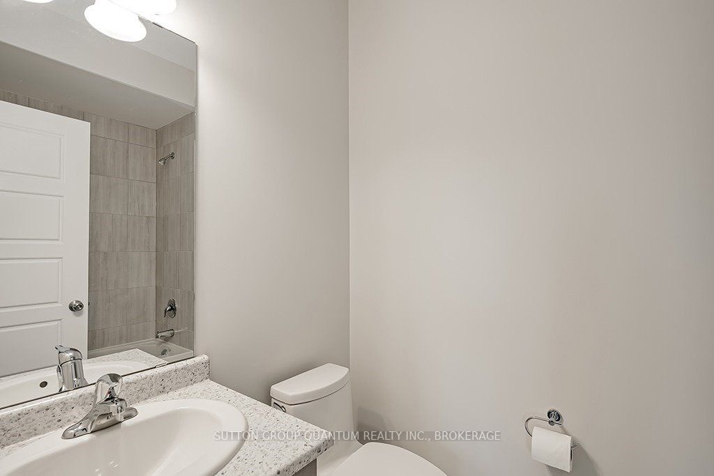 A bathroom with white walls and a toilet, sink and mirror.