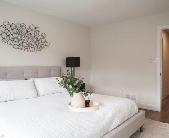 A bed room with a white bed and a vase on the table