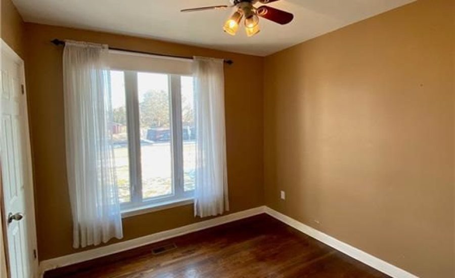 A room with a ceiling fan and wooden floors.