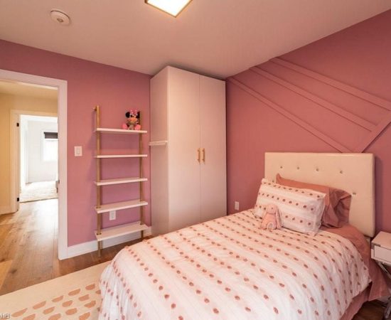 A bedroom with pink walls and white furniture.