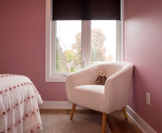 A bedroom with pink walls and white furniture.