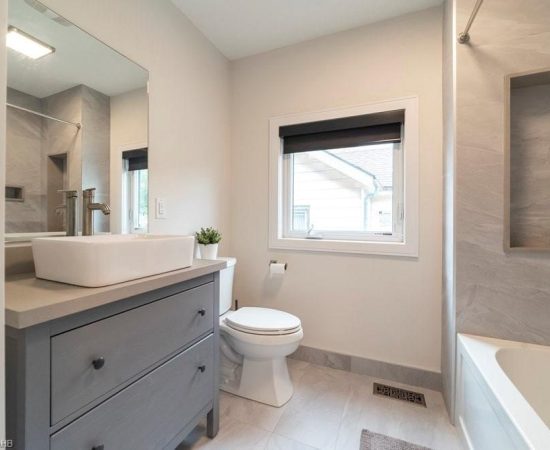 A bathroom with a toilet, sink and mirror.