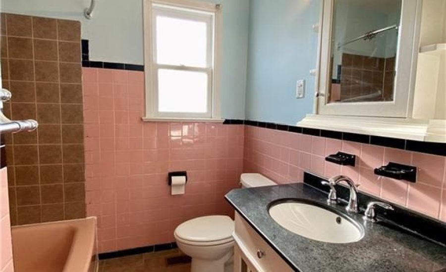 A bathroom with pink and blue walls, a toilet, sink and tub.