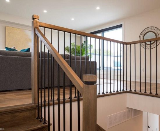 A wooden staircase with metal railing in the middle of it.