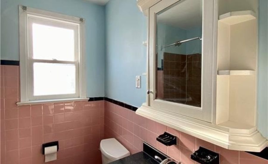 A bathroom with pink and blue walls, black counter top.