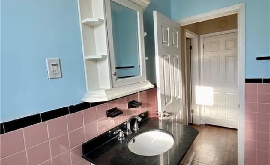 A bathroom with pink and blue tiles, black counter top.