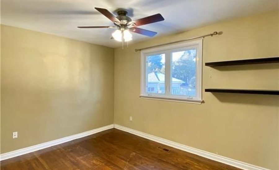 A room with a ceiling fan and two shelves.