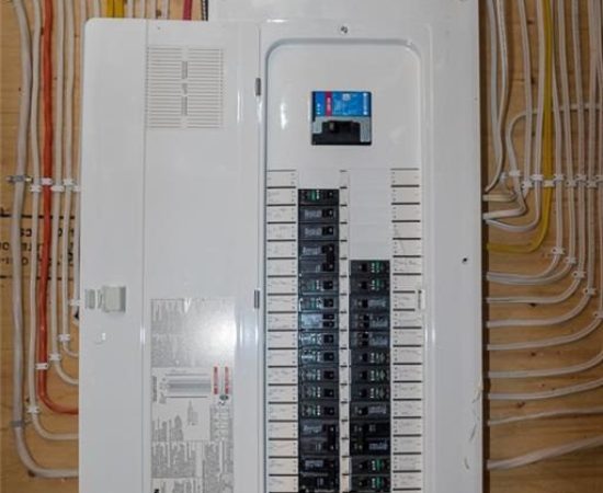 A white electrical panel with wires hanging from the ceiling.