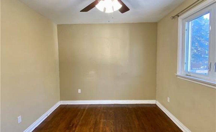 A room with a ceiling fan and wooden floors.