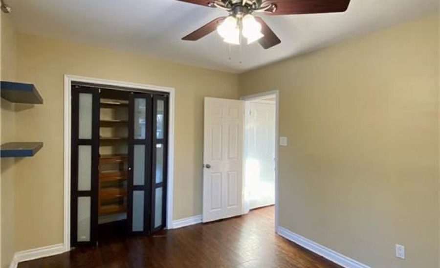 A room with a ceiling fan and wooden floors.