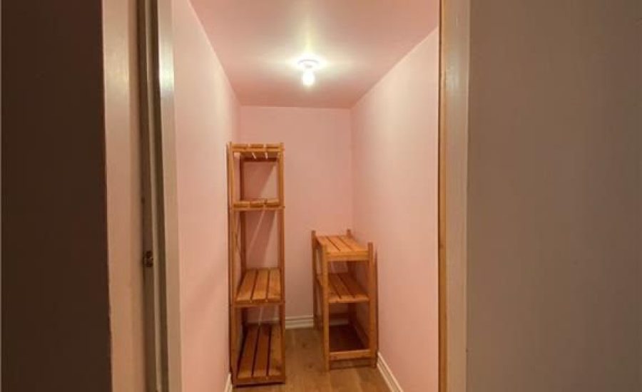 A hallway with shelves and a wooden floor.