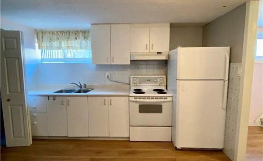 A kitchen with white cabinets and wooden floors.