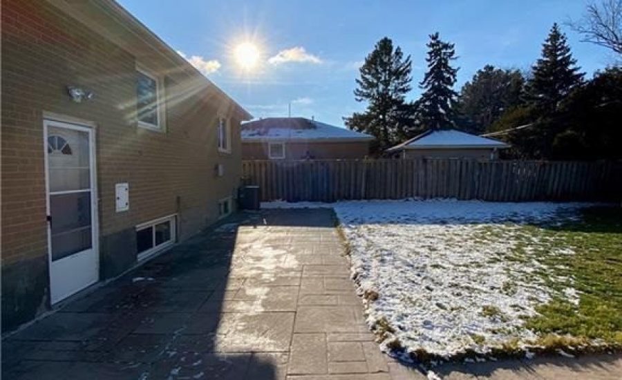 A backyard with snow on the ground and sun shining.