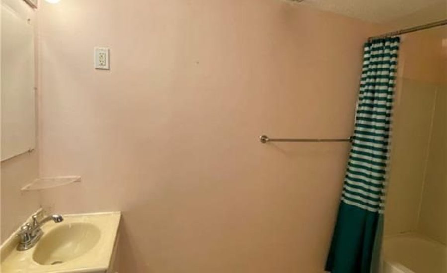 A bathroom with pink walls and white fixtures.