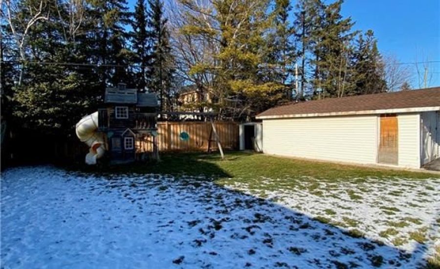 A backyard with snow on the ground and trees.