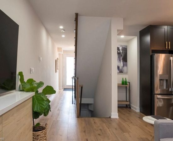 A hallway with a plant and a refrigerator.