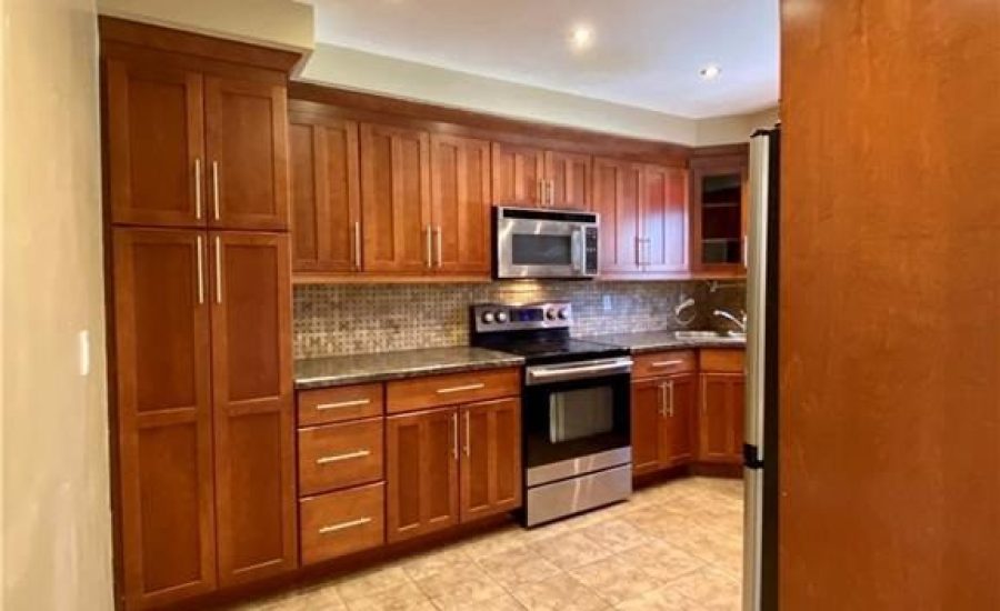 A kitchen with wooden cabinets and tile floors.