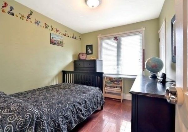 A bedroom with a bed, desk and dresser.