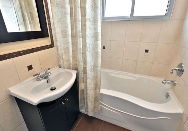 A bathroom with a sink, mirror and tub.