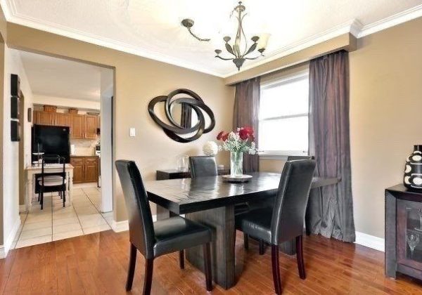 A dining room table with four chairs and a mirror.