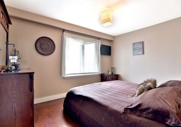 A bedroom with a bed, dresser and window.