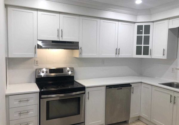 A kitchen with white cabinets and black appliances.