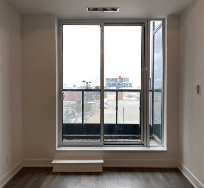 A room with a large window and wooden floors.