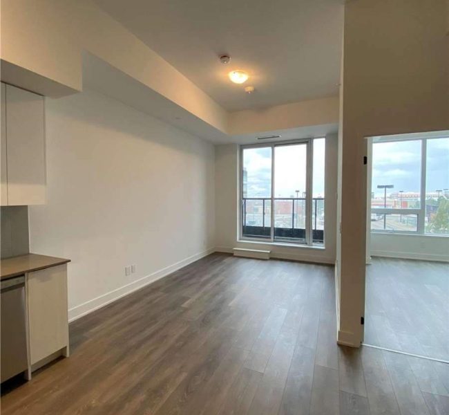 A living room with hard wood floors and large windows.