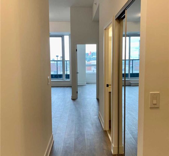 A hallway with a door open and a window in the background.