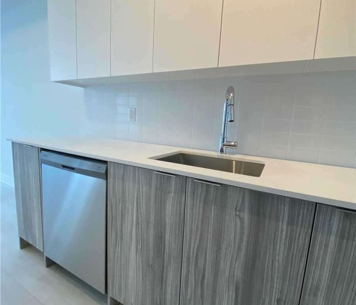 A kitchen with white cabinets and grey wood cupboards.