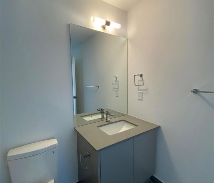 A bathroom with a toilet, sink and mirror.