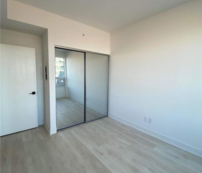 A bedroom with white walls and wooden floors.