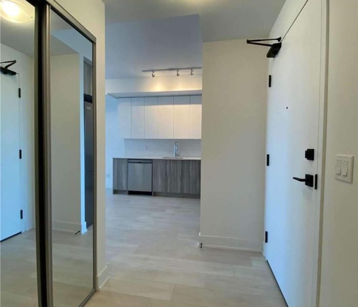 A hallway with two mirrors and a kitchen in the background.