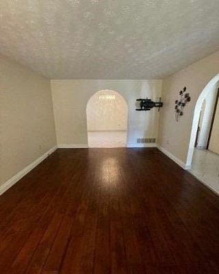 A room with hard wood floors and white walls.