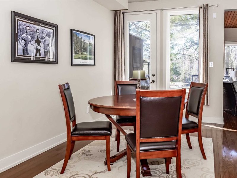 A dining room table with four chairs and a rug.