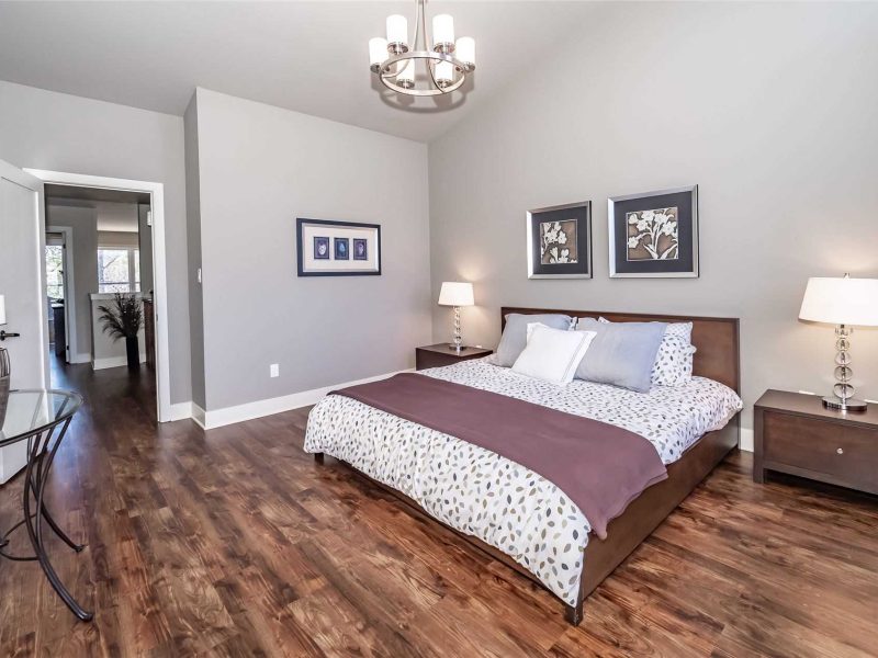 A bedroom with hard wood floors and a large bed.