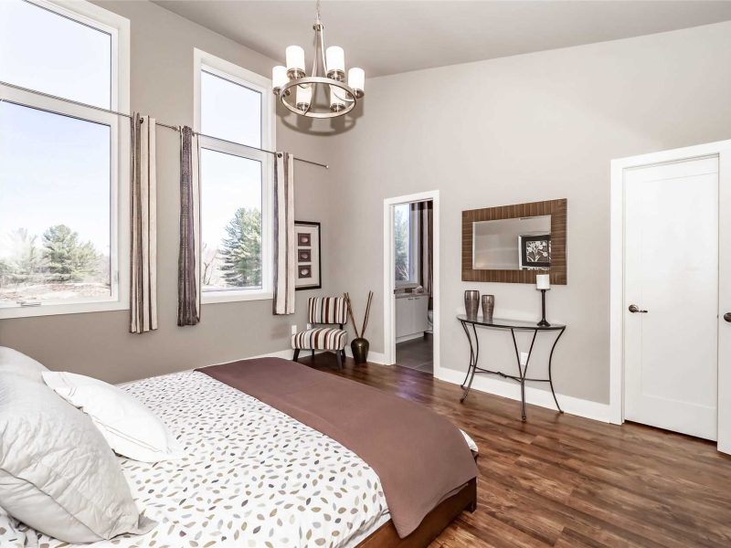 A bedroom with hard wood floors and large windows.