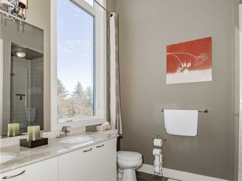 A bathroom with a large window and white cabinets