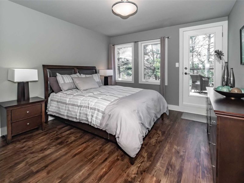 A bedroom with hard wood floors and a bed.