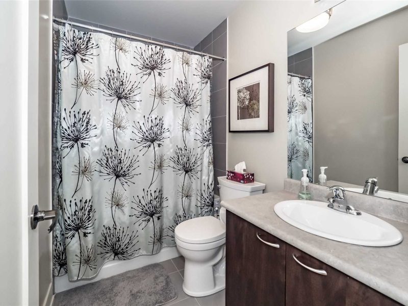 A bathroom with a toilet, sink and shower.