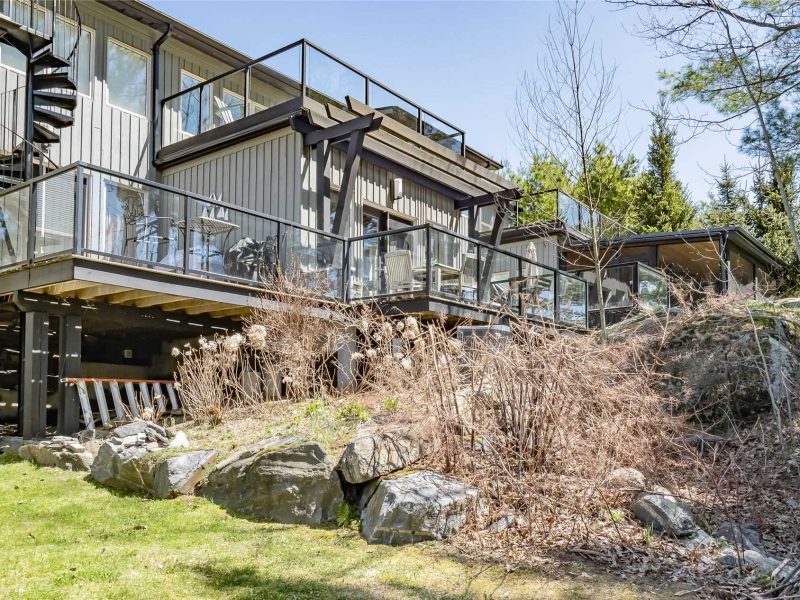 A house with a large rock wall and a deck.